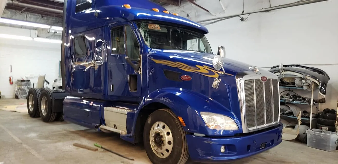 Blue Peterbilt sleeper with flame graphics in the shop bay
