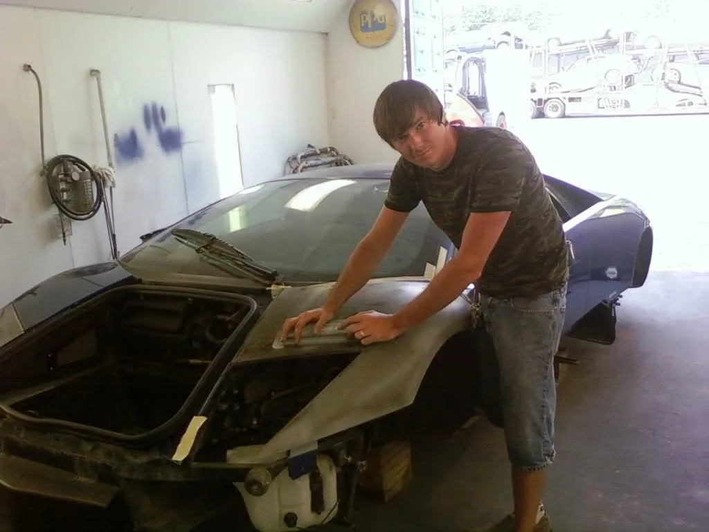 Technician hand sanding a Lamborghini hood in primer